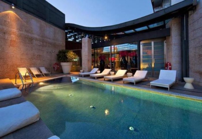 Urban Hotel's pool at dusk. This gay-friendly, pet-friendly hotel offers a relaxing outdoor space with lounge chairs for sunbathing and swimming.