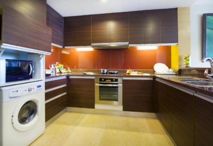 Urbana Sathorn Bangkok gay-friendly hotel kitchen. Modern design with wood cabinets, oven, microwave, washing machine, and sink. Bangkok travel.