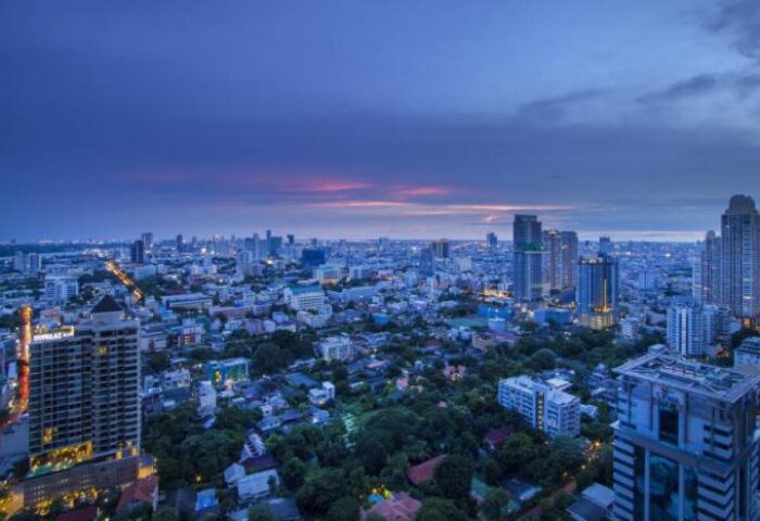 Urbana Sathorn Bangkok gay-friendly hotel aerial view at dusk. Bangkok skyline with skyscrapers and lush greenery. Gay travel advice.