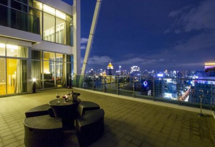 Urbana Sathorn Bangkok gay-friendly hotel balcony view at night. Rooftop seating with city skyline. Luxury travel for gay men in Thailand.