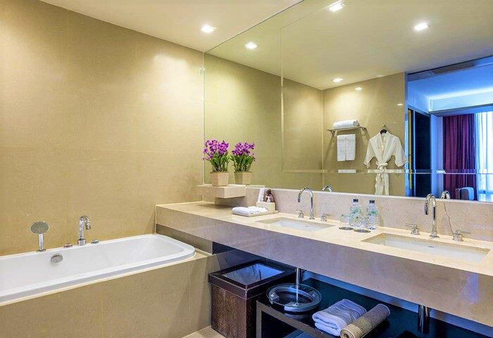 Bathroom at VIE Hotel Bangkok MGallery, a gay-friendly hotel. Features a bathtub, double sinks, large mirror, and modern design. Luxury travel.