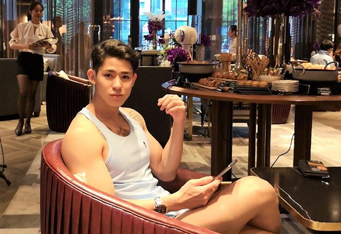 Gay-friendly VIE Hotel Bangkok - MGallery: A handsome man relaxes in a chair, using his phone in the hotel's stylish lounge area.