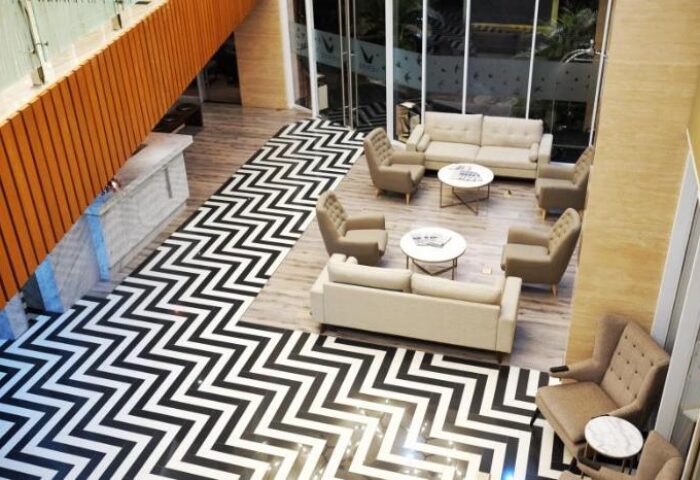 Verse Luxe Hotel Wahid Hasyim lobby. Gay-friendly hotel lounge area with sofas, armchairs, and a bold black and white zigzag floor pattern.