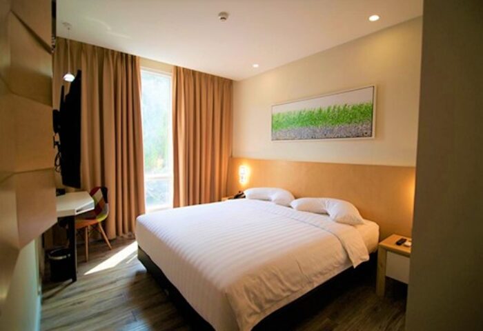 Verse Luxe Hotel Wahid Hasyim room. Gay-friendly hotel bedroom with a large bed, desk, and window. Modern design for gay travel in Jakarta.