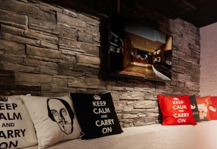 Via Hotel Taipei Station room featuring a stone wall, TV, and Keep Calm pillows. Gay-friendly hotel design detail.