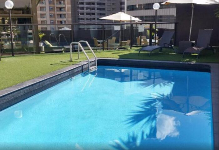 Vibe Hotel Sydney pool area. Gay-friendly hotel with outdoor pool, lounge chairs, and umbrellas. Perfect for relaxing during your Sydney trip.
