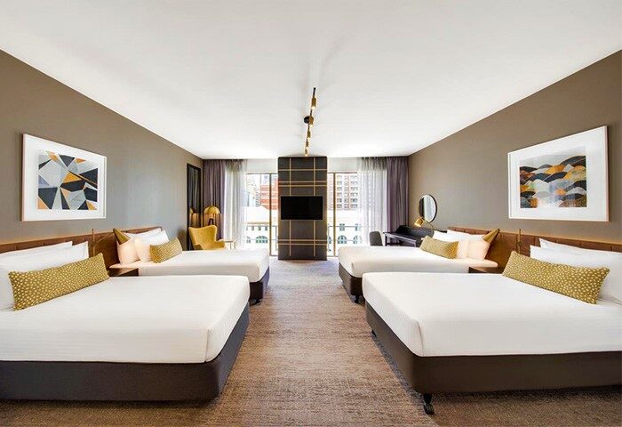 Vibe Hotel Sydney room. Gay-friendly hotel with 4 beds, desk, chair, and TV. Great for gay group travel in Sydney, Australia. Modern design.