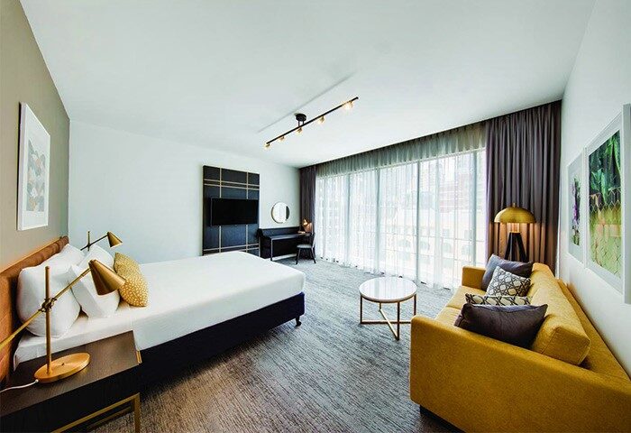 Vibe Hotel Sydney room. Gay-friendly hotel with bed, sofa, desk, and city view. Modern interior design at Vibe Hotel Sydney for gay travelers.