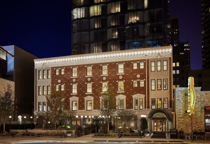 Viceroy Chicago hotel exterior at night. Gay-friendly hotel with vintage brick facade and modern tower. Outdoor seating area. Chicago travel.
