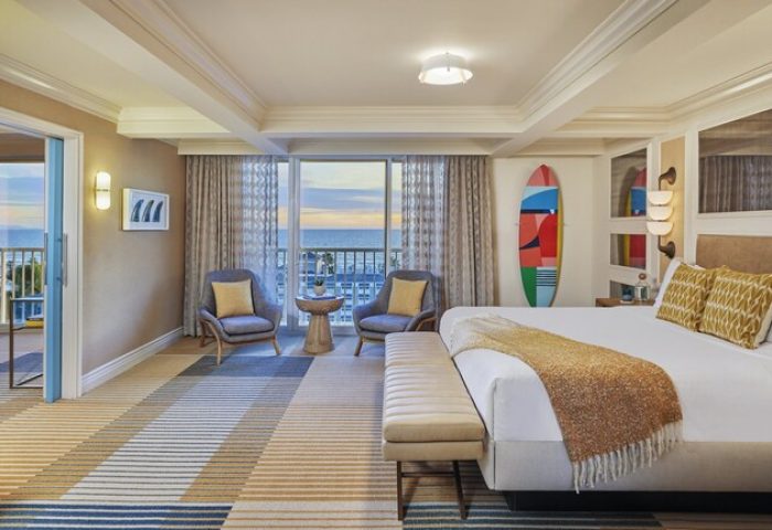 Viceroy Santa Monica gay-friendly hotel room. Ocean view, bed, chairs, and surfboard art. Upscale gay travel lodging.
