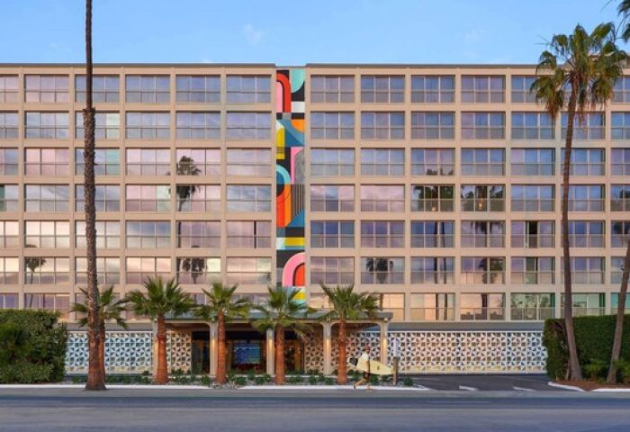 Viceroy Santa Monica, a gay-friendly hotel. Exterior view of the hotel with palm trees and a colorful mural. Gay travel destination.