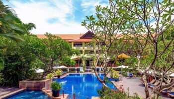 Victoria Angkor Resort & Spa pool view. Gay-friendly hotel with lush greenery, blue pool, and relaxing atmosphere. Perfect for gay travel.