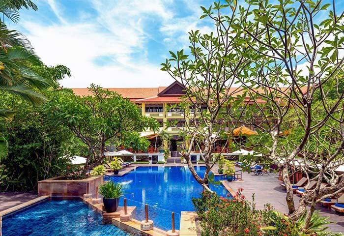 Victoria Angkor Resort & Spa pool view. Gay-friendly hotel with lush greenery, blue pool, and relaxing atmosphere. Perfect for gay travel.