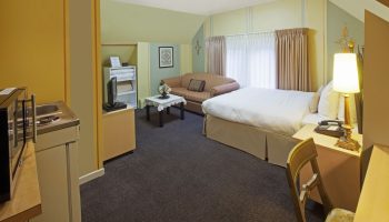 Victoria's Mansion Guest House room. Gay-friendly hotel with bed, sofa, kitchenette, desk, and chair. A cozy space for gay travelers.