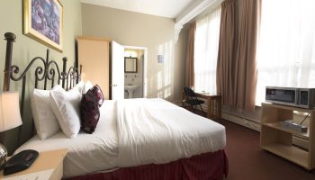 Victoria's Mansion Guest House, gay-friendly hotel room. Bed, desk, microwave, and bathroom visible. Ideal for gay travelers.