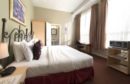 Victoria's Mansion Guest House, gay-friendly hotel room. Bed, desk, microwave, and bathroom visible. Ideal for gay travelers.