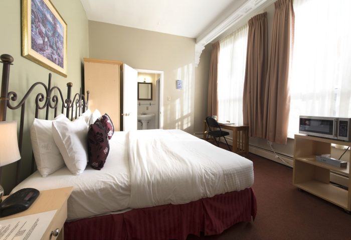 Victoria's Mansion Guest House, gay-friendly hotel room. Bed, desk, microwave, and bathroom visible. Ideal for gay travelers.