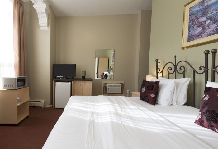 Victoria's Mansion Guest House room. Gay-friendly hotel with bed, TV, mini-fridge, microwave, and air conditioning. Comfortable stay.