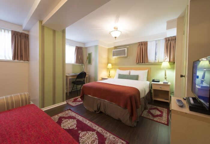 Victoria's Mansion Guest House room. Gay-friendly hotel bedroom with bed, desk, TV, and red accents. Ideal for gay men travel.