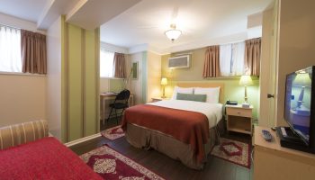 Victoria's Mansion Guest House room. Gay-friendly hotel bedroom with bed, desk, TV, and red accents. Ideal for gay men travel.
