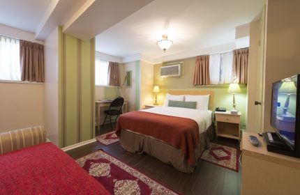 Victoria's Mansion Guest House room. Gay-friendly hotel bedroom with bed, desk, TV, and red accents. Ideal for gay men travel.