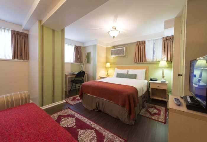 Victoria's Mansion Guest House room. Gay-friendly hotel bedroom with bed, desk, TV, and red accents. Ideal for gay men travel.