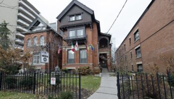Victoria's Mansion Guest House, a gay-friendly hotel. Flags wave outside this brick building, a welcoming LGBTQ+ travel destination.