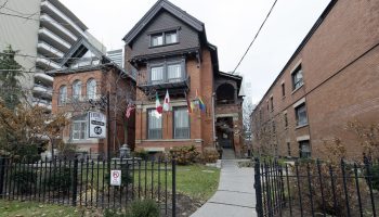 Victoria's Mansion Guest House, a gay-friendly hotel. Flags wave outside this brick building, a welcoming LGBTQ+ travel destination.