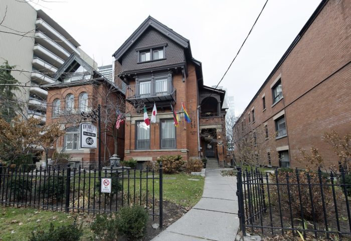 Victoria's Mansion Guest House, a gay-friendly hotel. Flags wave outside this brick building, a welcoming LGBTQ+ travel destination.