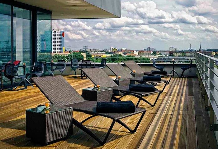 Rooftop terrace at Vienna House Andel's Berlin, a gay-friendly, pet-friendly hotel. Lounge chairs offer city views. Ideal for gay travel.