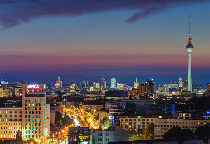 Berlin skyline at dusk with the TV Tower. Vienna House Andel’s Berlin, a gay-friendly & pet-friendly hotel, is visible in the foreground.