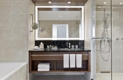 Vienna Marriott Hotel bathroom. Modern design with a large mirror, dark countertop, and glass-enclosed shower. Gay-friendly hotel.