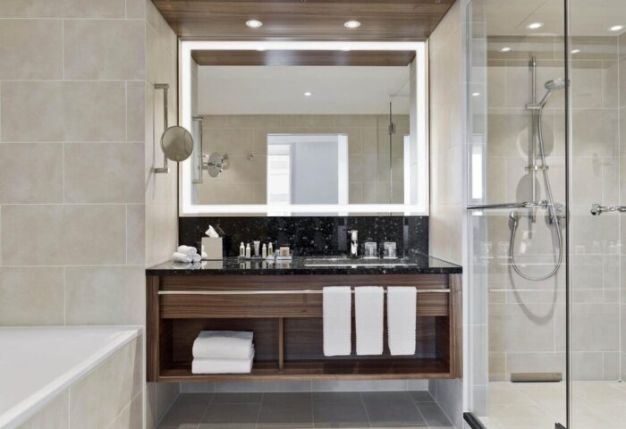 Vienna Marriott Hotel bathroom. Modern design with a large mirror, dark countertop, and glass-enclosed shower. Gay-friendly hotel.