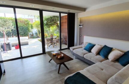 Villa Adler Gay Men Only lounge area with a view to the garden. Gay-friendly hotel interior with sofa, table, and outdoor seating.