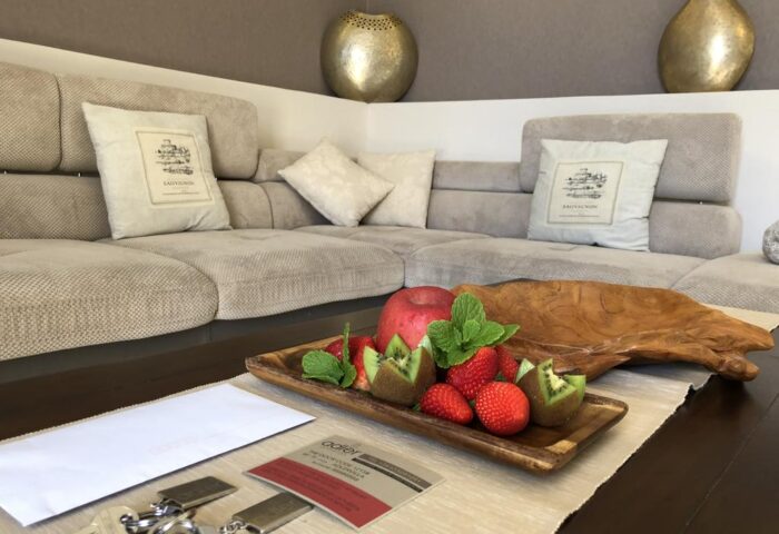 Villa Adler Gay Men Only hotel room detail. Fruit plate, keys, and a stylish sofa create a welcoming atmosphere. Gay-friendly hotel.