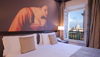 Villa Agrippina Gran Melia hotel room. Gay-friendly hotel with a view of Rome. Balcony, bed, and artwork on the wall.