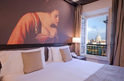 Villa Agrippina Gran Melia hotel room. Gay-friendly hotel with a view of Rome. Balcony, bed, and artwork on the wall.