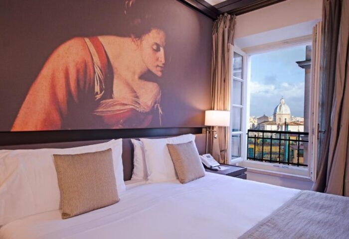 Villa Agrippina Gran Melia hotel room. Gay-friendly hotel with a view of Rome. Balcony, bed, and artwork on the wall.