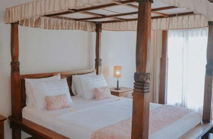 Villa Kresna Boutique and Suites gay-friendly hotel room. Four-poster bed with white linens, soft lighting, and elegant decor. Relaxing space.