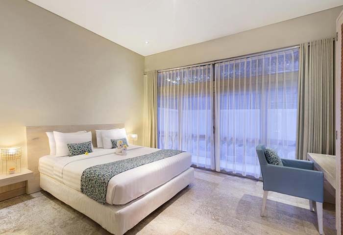Villa Kresna Boutique and Suites gay-friendly hotel room. King bed, sheer curtains, desk, and chair. Luxury gay travel in Seminyak, Bali.