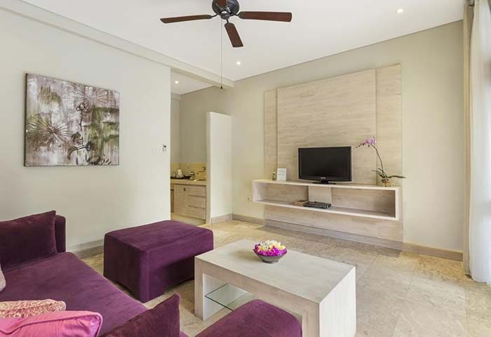 Villa Kresna Boutique gay-friendly suites' living room. Purple sofa, TV, ceiling fan, and modern decor. Ideal gay travel hotel.