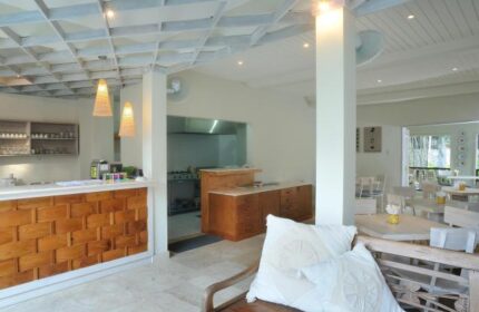 Villa Kresna Boutique and Suites interior. Gay-friendly hotel with kitchen, dining area, and wooden bench with pillows. Boutique hotel design.