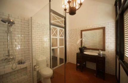 Villa Samadhi Singapore bathroom. Shower, toilet, and sink. The gay-friendly hotel features vintage design, white brick tiles and terracotta floor.