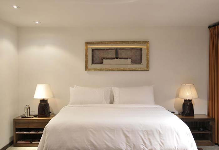 Villa Samadhi by Samadhi, gay-friendly hotel. Bedroom with a king-size bed, bedside tables with lamps, and framed artwork. Minimalist design.