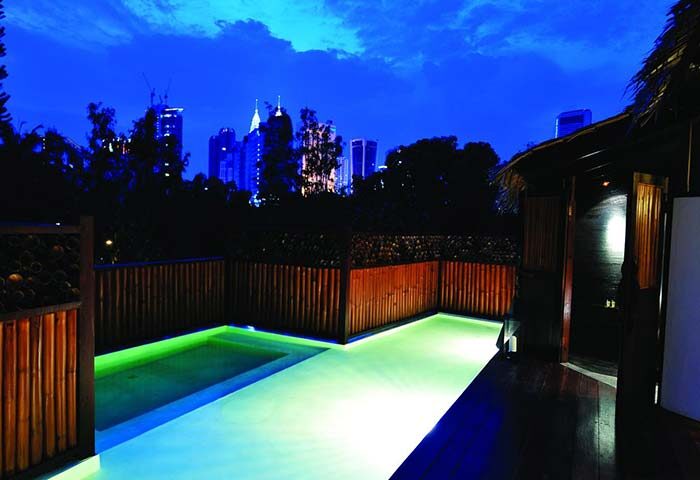 Villa Samadhi by Samadhi gay-friendly hotel at night. Poolside view with city skyline. Luxury travel for gay men.