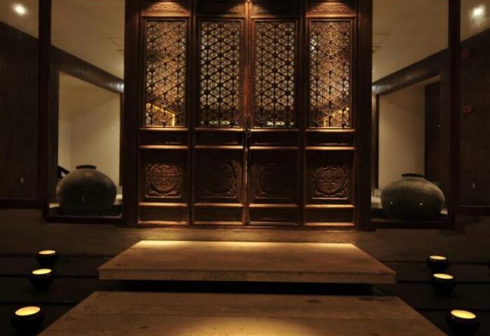 Villa Samadhi by Samadhi entrance. Gay-friendly hotel with carved wooden doors, stone steps, and ambient lighting. Luxury travel for gay men.