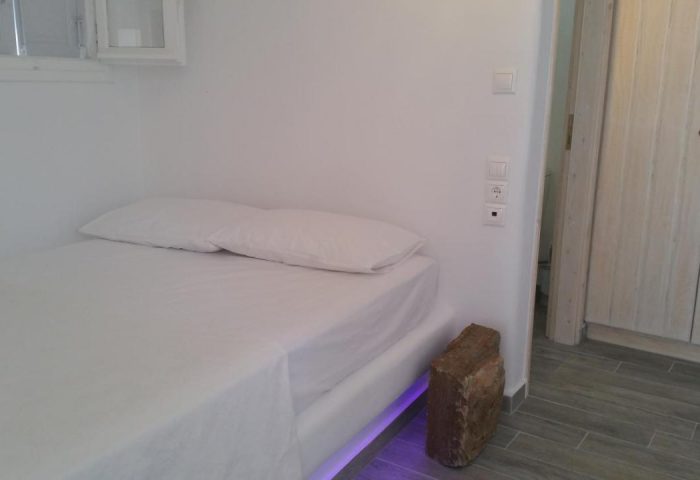 Villa Varnali Small Boutique gay-friendly hotel room. Minimalist white decor, bed with white linens, stone accent, and closet.
