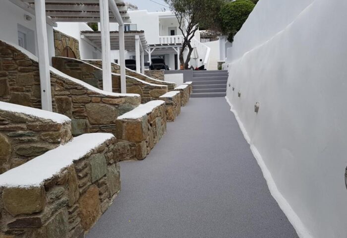 Villa Varnali Small Boutique, a gay-friendly hotel. Exterior view of stone walls and white buildings, typical of Greek island architecture.