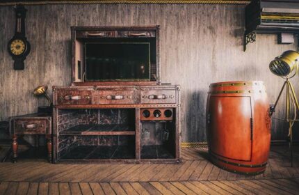 Vintage Luxury Yacht Hotel room decor. Leather trunk-style furniture, barrel bar, clock, and spotlight. Gay-friendly hotel design.