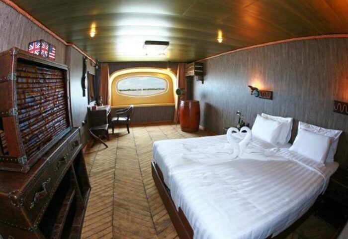 Vintage Luxury Yacht Hotel room. Gay-friendly hotel interior with a bed, swan towels, and nautical decor. Unique travel experience.